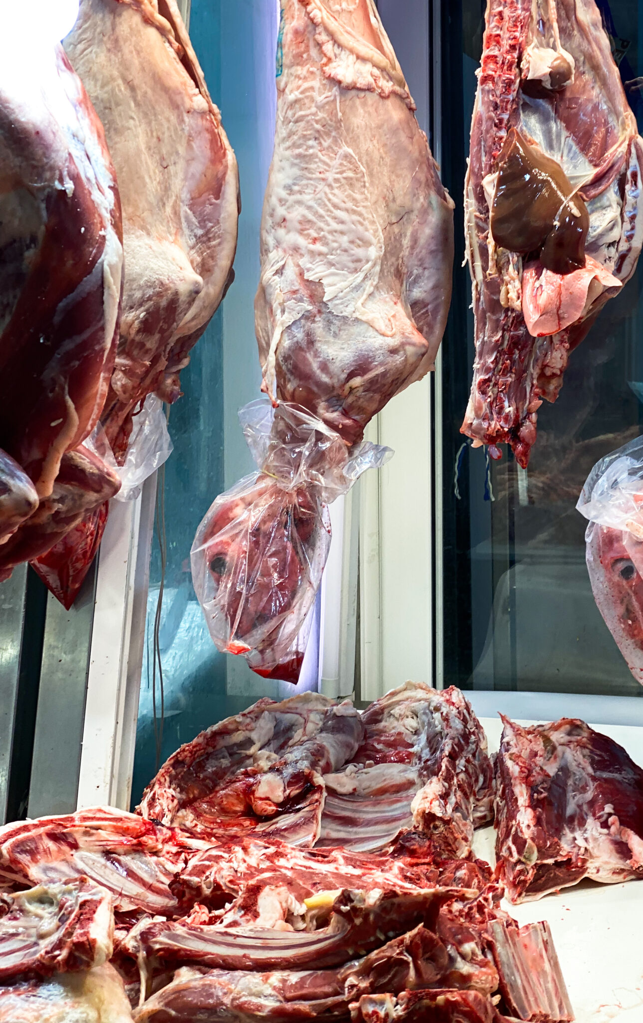 Large sheep carcasses hanging in butcher section Athens food market