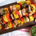 3 skewers of corn and salmon shashlik on a wooden cutting board